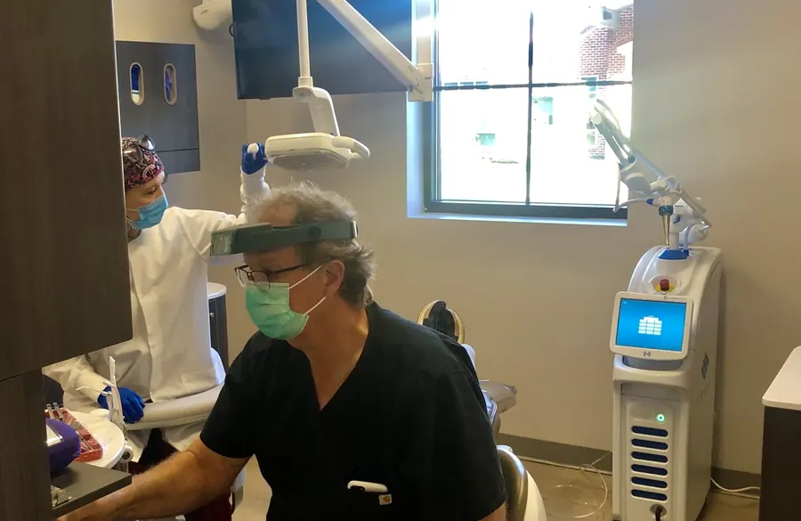Dr. Dean treating a patient, with the Solea laser unit beside the chair.